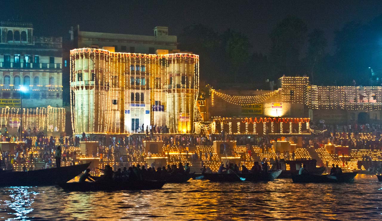 Boats on the Ganga in front of illuminated ghat buildings during Dev Diwali Varanasi